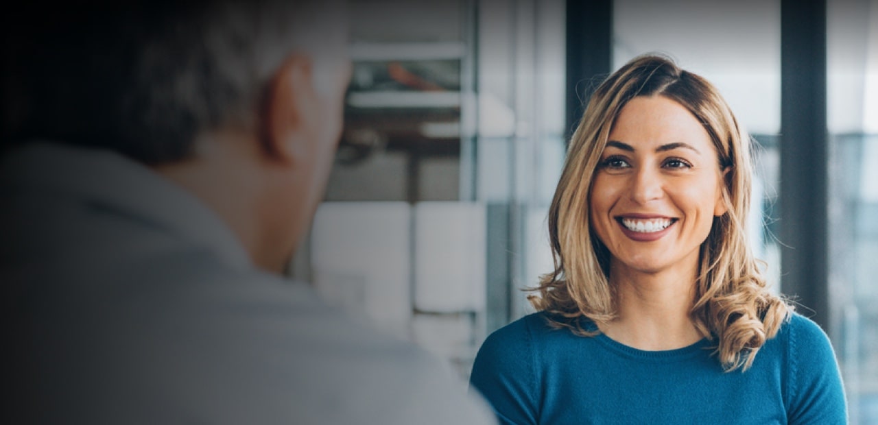 A smiling women in blue t shirt explaining a man
