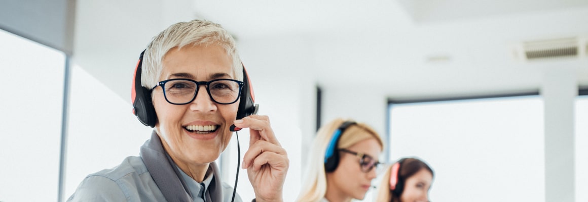 A smiling woman speaking over headset